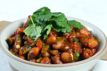 Stewed broad beans in tomato sauce with herbs and spices close-up,