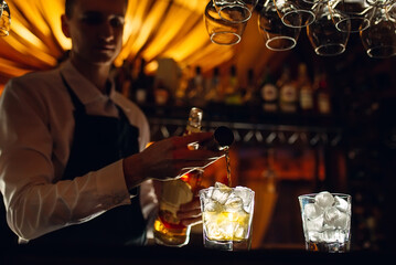 The bartender pours whiskey on the bar.