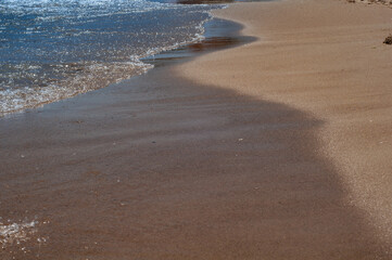 Fototapeta na wymiar Sandy seashore with surging sea wave, yellow sandy beach close up