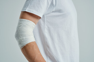 male patient in a white T-shirt with a bandaged hand light background
