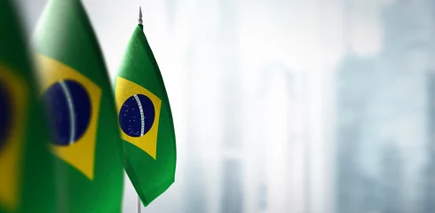 Selbstklebende Fototapete Brasilien Kleine Flaggen von Brasilien auf einem verschwommenen Hintergrund der Stadt