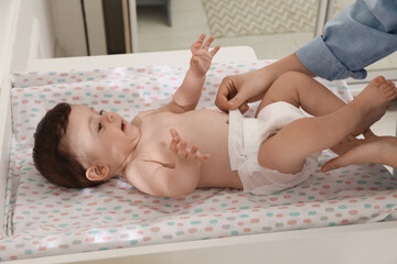 Mother changing baby's diaper on table at home, closeup