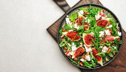 Sweet fig salad with soft goat cheese, walnuts, arugula and jam dressing on white background, top view, copy space