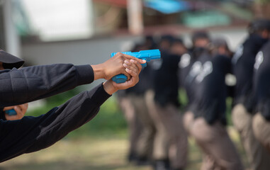 Police practice using blue rubber firearms in the lawn.
