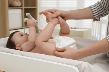 Mother changing baby's diaper on table at home, closeup - obrazy, fototapety, plakaty