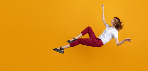 Studio shot of young cute girl isolated falling down isolated on yellow color studio background. Concept of human emotions, facial expression