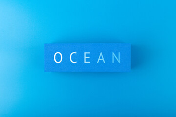 Single word ocean on dark blue background with gradient. Concept of ocean pollution with plastic garbage, ecology poster or Ocean day poster or banner