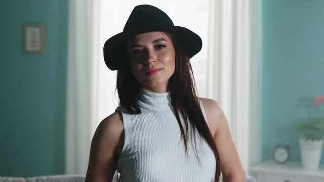 Portrait of young beautiful woman, brunette in white top and black hat, standing and looking at camera, tender and feminine, Foreground, Slow motion.