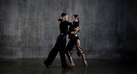 Fototapeta na wymiar The young dance ballroom couple in black dress dancing in sensual pose on studio background. Professional dancers dancing latino. Ballroom dance concept. Human emotions - love and passion