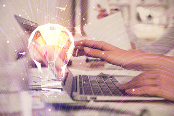 Double exposure of woman hands typing on computer and light bulb drawing. Idea concept.