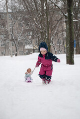 Fototapeta premium a child sledded a doll in a winter suit for the new year and Christmas in the winter