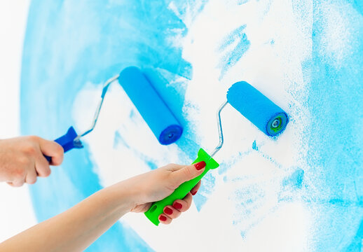 blue color painting wall with roller in hand.