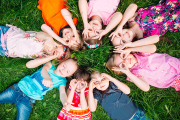 Fototapeta premium A group of children lying on the green grass in the Park. The interaction of the children.