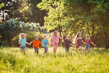 Large group of kids, friends boys and girls running in the park on sunny summer day in casual...