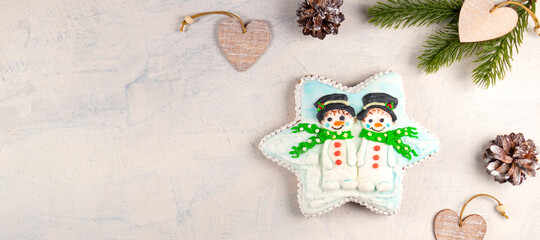 banner with Christmas gingerbread with snowmen on a gray background with fir branches and cones. soft focus. top view
