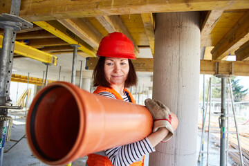 Frau als Handwerker trägt ein Wasserrohr aus Plastik - obrazy, fototapety, plakaty