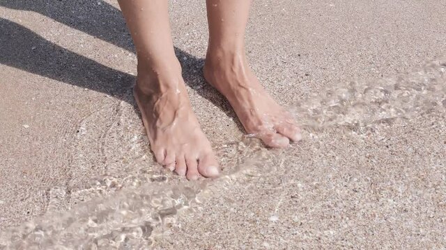 Woman feet in the water on the beach sea. 4k video footage quality. Marine theme