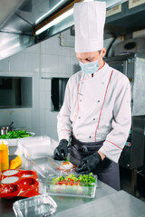 Food delivery in the restaurant. The chef prepares food in the restaurant and packs it in disposable dishes.