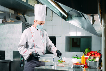 Food delivery in the restaurant. The chef prepares food in the restaurant and packs it in disposable dishes.