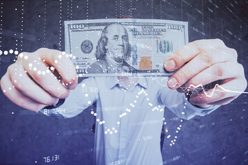 Double exposure of technology drawing hologram and us dollars bills and man hands. Data concept