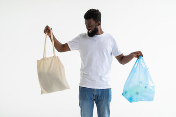 Zero waste concept. African american black men choose mesh bag and plastic package isolated over white background with free space.