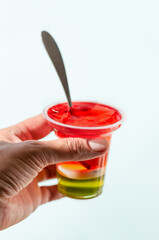 A female hand holds a glass of fruit jelly. Vertical crop. Close up.