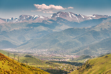 Aerial view from afar of the city at the foot of the high mountains. Travel to the Caucasus