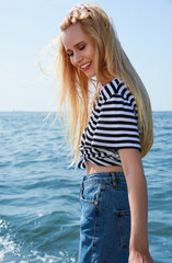 Beautiful young woman near sea on sunny day in summer