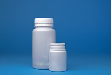 White bottles with pills on blue background. Plastic bottles. Medicine.