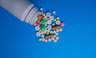 Pills from the bottle on blue background. Pharmaceutics.