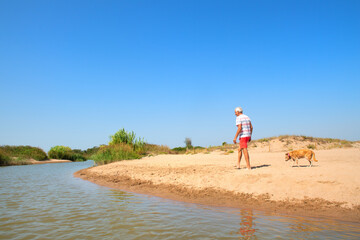 Senior man walking with old dog at beach