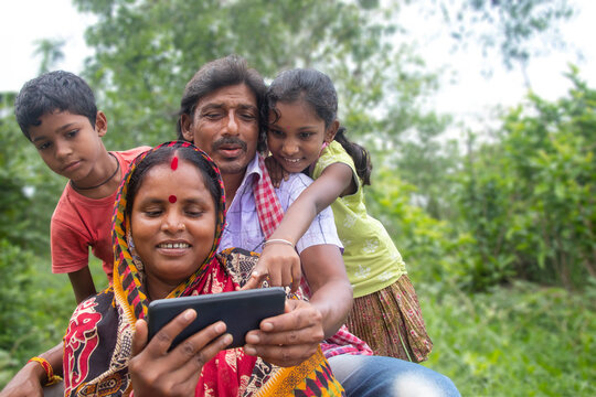 Indian Rural Parents and their two children watching movie in agricultural field