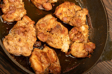 Fried pieces of meat in a frying pan, close-up, selective focus.