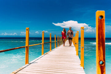 A beautiful couple walks along the pier of paradise island in warm sunny weather. A happy couple is...