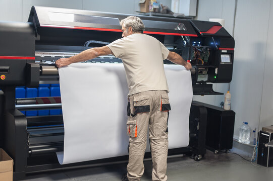 Technician operator works on large premium industrial printer plotter machine