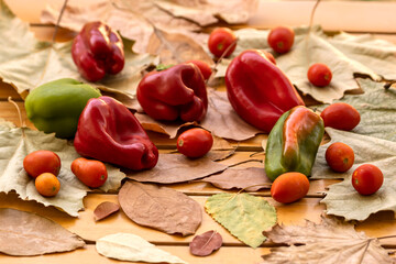 Obraz na płótnie Canvas Peppers and tomatoes among autumn leaves 