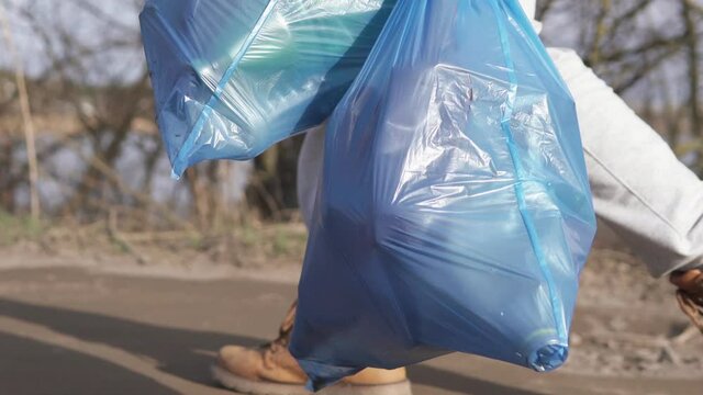 A volunteer collected rubbish in the forest and carries it to trash cans.
