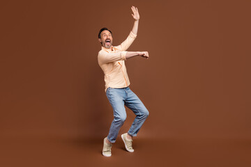 Photo of crazy funky guy dance imagine ride horse wear beige shirt jeans shoes isolated brown color background