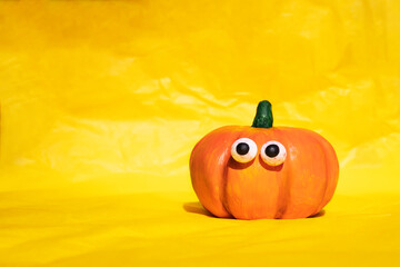 Funny pumpkin with eyes on a yellow background. Side view, place for text.