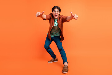 Full size photo of excited smiling cheerful male showing thumb-up you feedback advertise isolated on orange color background