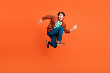 Fototapeta na wymiar Full size photo of cheerful good mood man running in air traveling wear brown shirt isolated on orange color background