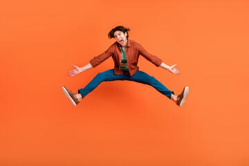 Obraz premium Full size photo of funky funny man jumping unhappy shrug shoulders fooling around isolated on orange color background