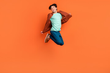 Full size photo of funky smiling cheerful carefree man jumping enjoy summer vacation isolated on orange color background