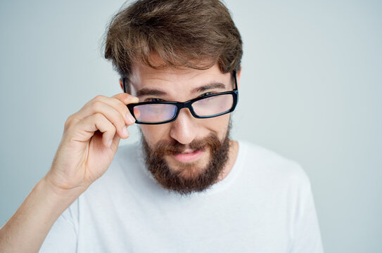 bearded man with glasses in hand vision problems light background