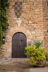 Fototapeta na wymiar pintoresca puerta de madera en muro castillo de montsonis con escudo medieval