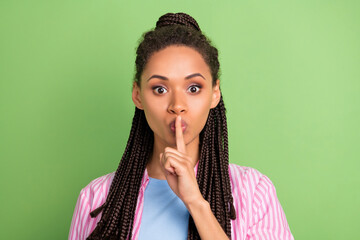 Photo of young silent mute afro american woman hold finger mouth tell secret isolated on green...