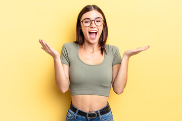 hispanic pretty woman feeling happy, excited, surprised or shocked, smiling and astonished at...