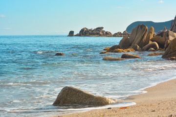 The sandy beach, rocks and stones go into the sea. The weather is good at sea. - 458232885