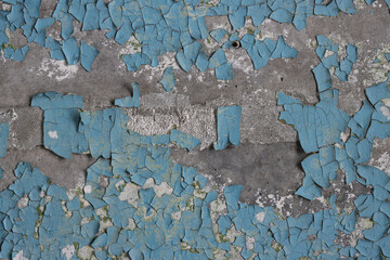 Blue peeling paint on the wall. Old concrete wall with cracked flaking paint. Weathered rough painted surface with patterns of cracks and peeling. High resolution texture for background and design.