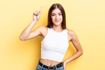 hispanic pretty woman smiling cheerfully and happily, pointing upwards with one hand to copy space